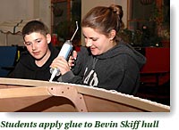 Students apply glue to Bevin skiff hull